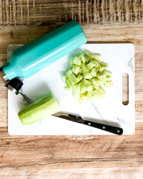 Diced cucumbers on a cutting board with empty storage container