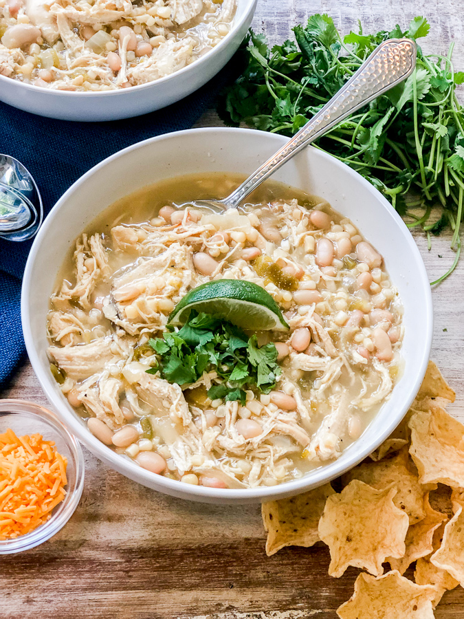 White Chicken Chili in a bowl with tortilla chips and cheese