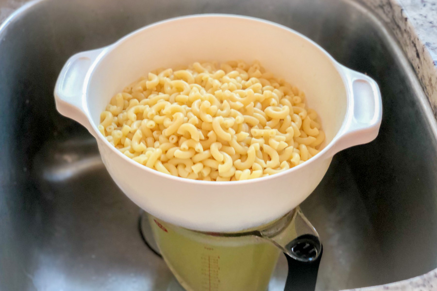 Draining macaroni into a measuring cup