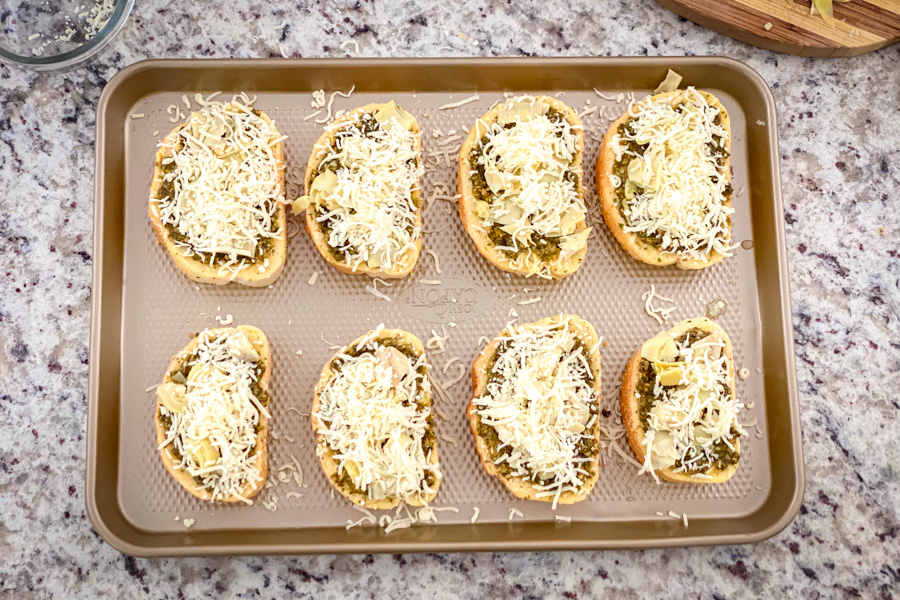 5 Cheese Texas Toast with added pesto, cheese, and artichoke on a baking sheet