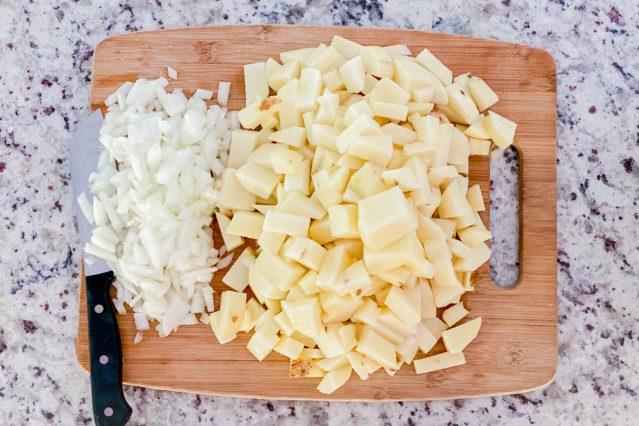 Diced onions and potatoes on a cutting board. 