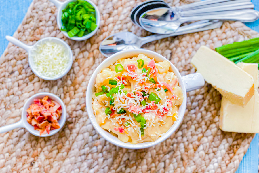 Our Easy Bacon Potato Soup in a bowl with bacon, cheese, and green onion garnishes around it. 