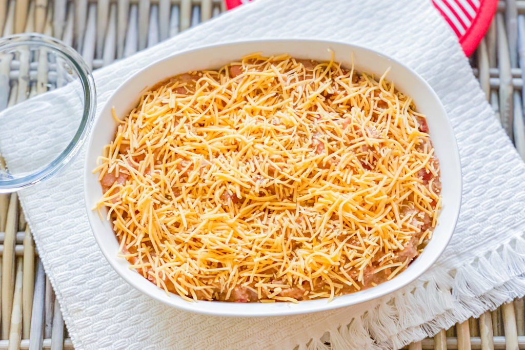 A baking dish with a bean mixture in it, topped with cheese. 