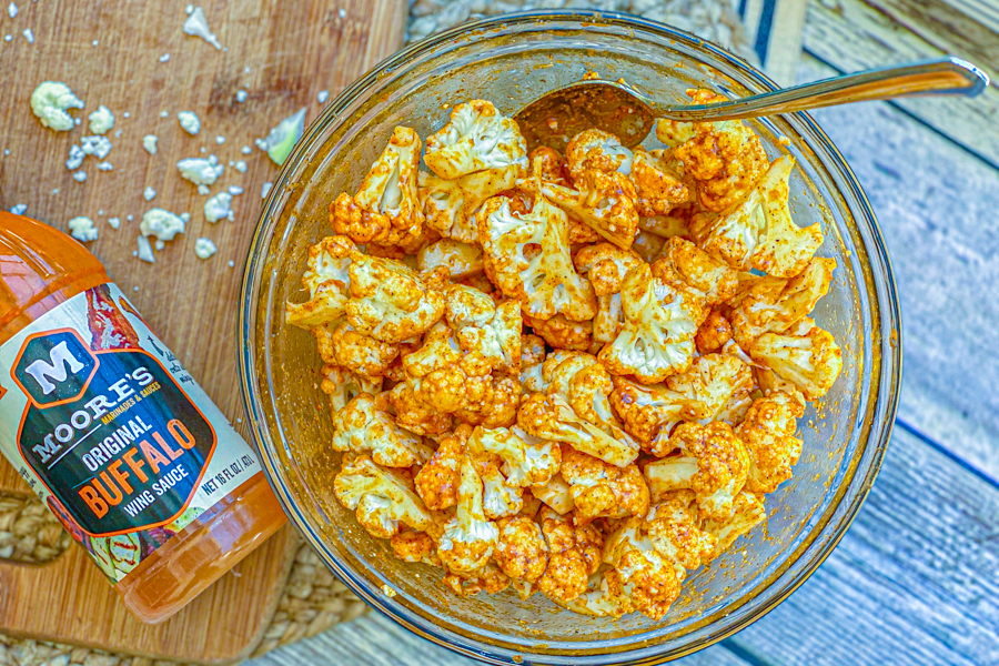 Cauliflower florets in a clear bowl with  buffalo sauce. 